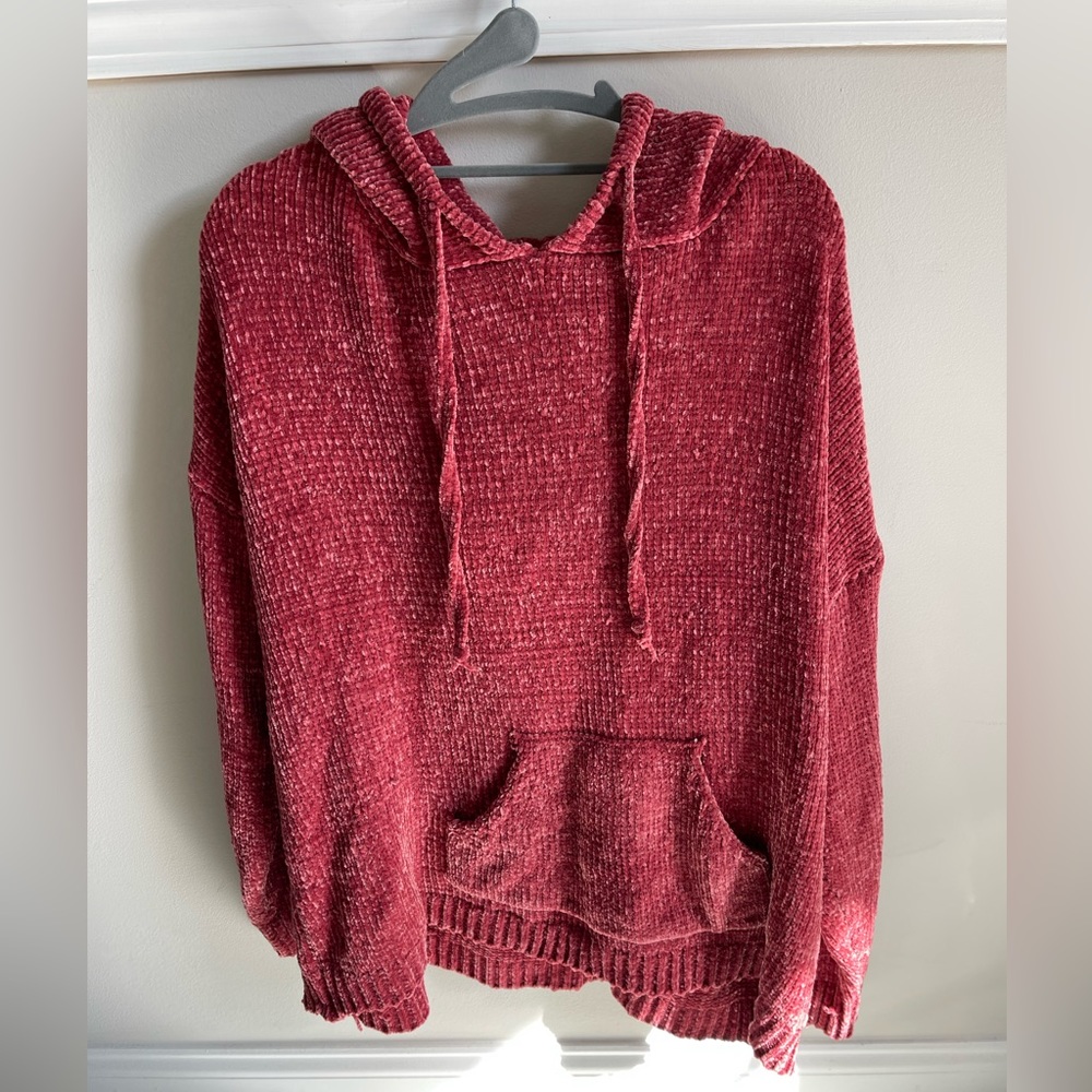 Reddish loose sweater with a hood, lightly worn.